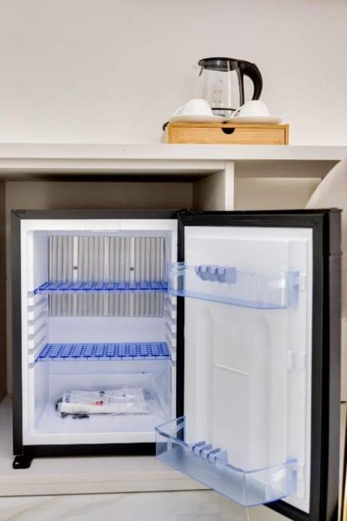 Piccolo frigorifero con porta aperta nella Deluxe King Room di Domus Praeclara Merulana Roma