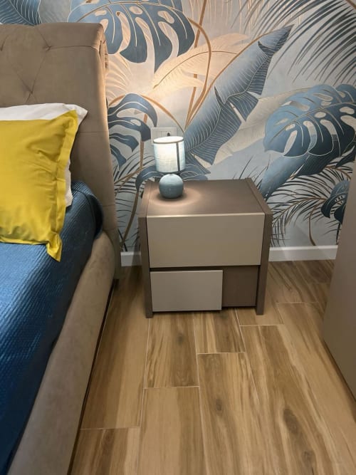 Camera moderna all'Anima Est Naples B&B con poltrona beige, cuscino giallo, comodino e carta da parati a foglie tropicali