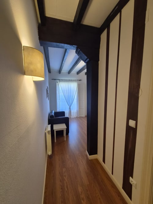 Hallway at Posada Torre del Milano hotel in Comillas with wooden floors and dark beams leading to guest room
