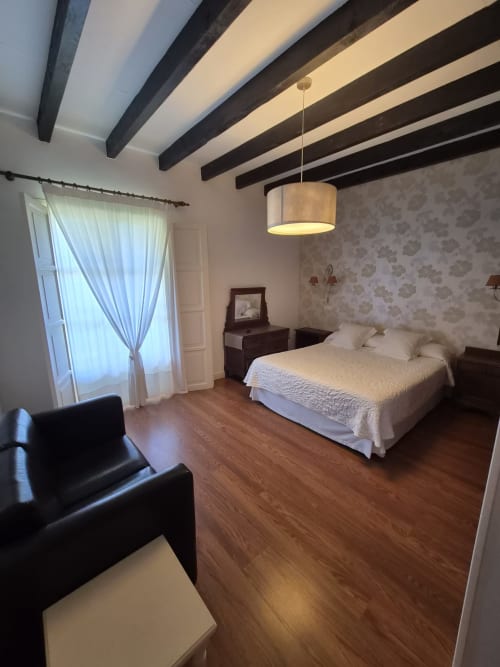 Spacious bedroom at Posada Torre del Milano in Comillas with exposed beams, queen bed, wooden floors, and sea view access