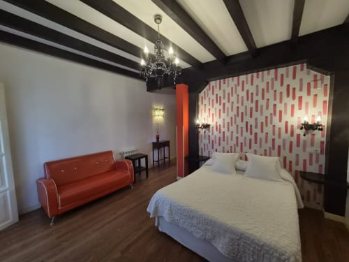Moderno dormitorio doble en Posada Torre del Milano de Comillas con pared de acento rojo, mobiliario contemporáneo y lámpara de araña