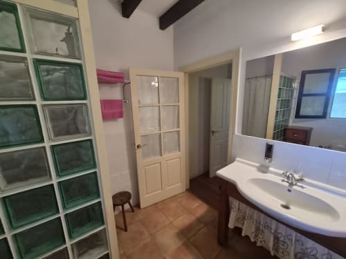 Spacious bathroom at Posada Torre del Milano in Comillas with sink, shower, and terracotta tile flooring