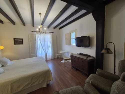 Spacious double bedroom at Posada Torre del Milano in Comillas with exposed beams, TV, and sea view access