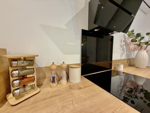 Comptoir de cuisine moderne avec étagère à épices en bois, pot de sel, moulins à poivre et fleurs en pot à la villa Côte Landes