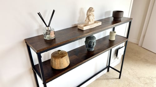 Console moderne aux étagères en bois foncé et structure métallique, présentant objets de décoration et plantes dans une villa de la Côte Landes