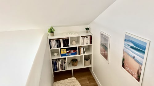Coin de lecture douillet à la villa LOCATION COTE LANDES avec étagères blanches, livres, plantes et art côtier à Pontenx-les-Forges