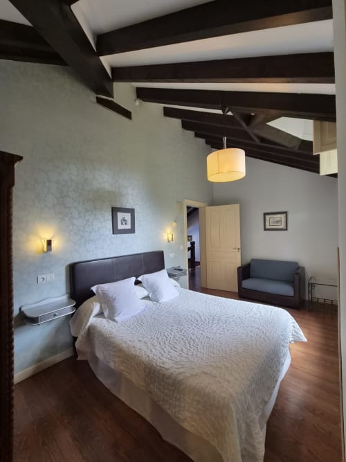 Modern double bedroom at Posada Torre del Milano in Comillas with beamed ceiling, queen bed, and mountain views