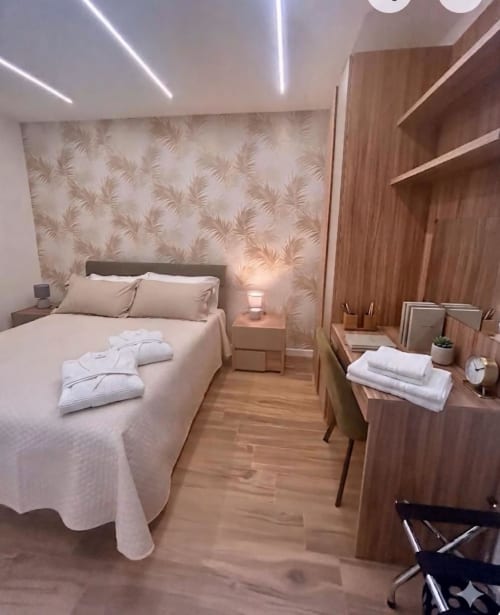 Camera moderna all'Anima Est Naples B&B con letto matrimoniale, mobili in legno, carta da parati con motivi floreali e luci lineari a soffitto
