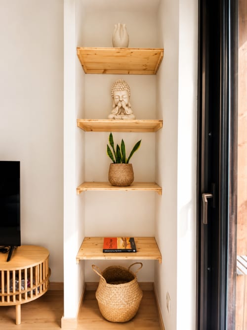 Nicho com prateleiras de madeira na Terra Clara Studio com busto de Buda, vaso cerâmico, planta em vaso e cestos trançados