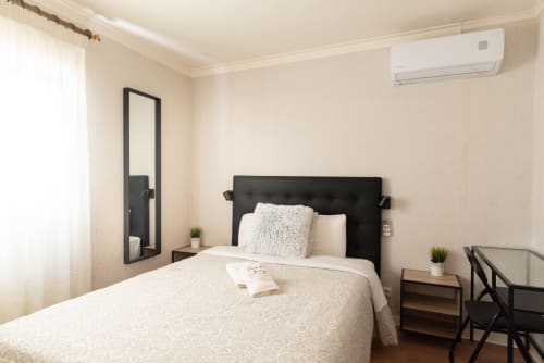 Modern bedroom at Charme da Graça hotel in Costa de Caparica, Lisboa with black headboard, white bedding, desk, and air