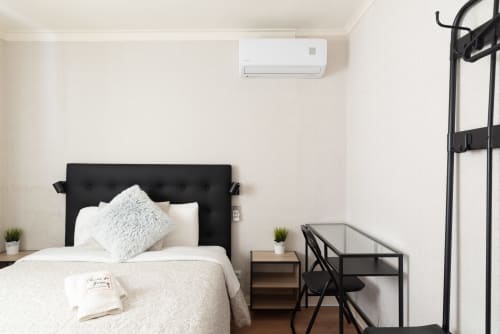 Modern bedroom at Charme da Graça hotel in Costa de Caparica, featuring black headboard, white bedding, air conditioning,