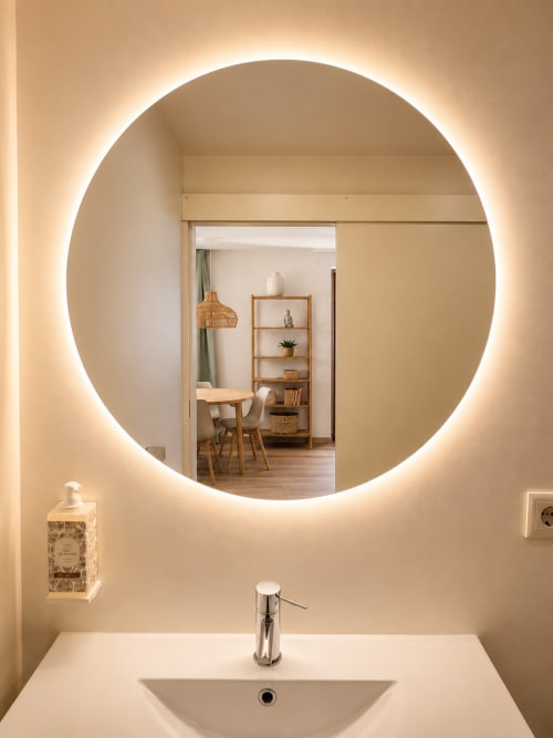 Espelho circular iluminado na casa de banho do Terra Clara Studio, Esposende, revelando o interior moderno do apartamento
