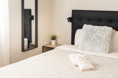 Modern bedroom at Charme da Graça hotel in Costa de Caparica, Lisbon with black headboard, white bedding, and fuzzy pillow