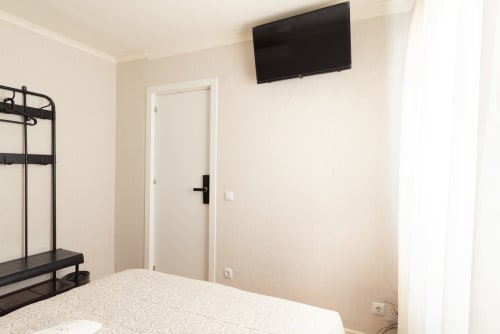 Modern apartment bedroom at Charme da Graça in Costa de Caparica, Lisboa with bed, TV, and minimalist décor