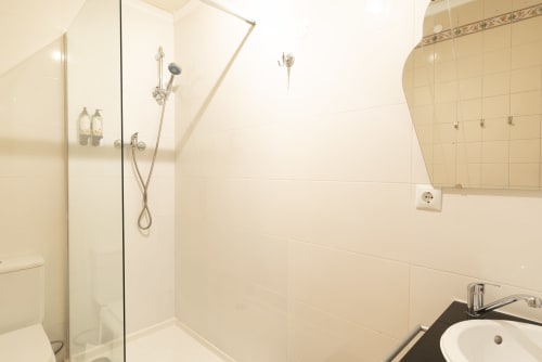 Modern bathroom at Charme da Graça in Costa de Caparica with walk-in shower, white tiles, and contemporary fixtures