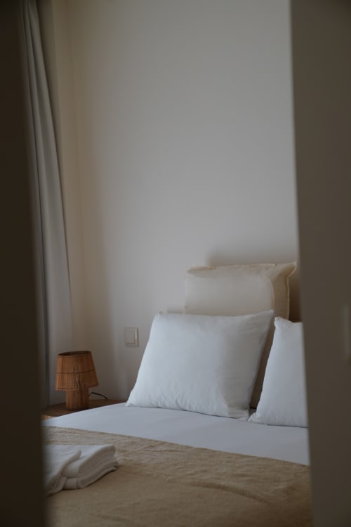 Minimalist bedroom at Terra Clara Studio with white pillows, wooden lamp, and neutral tones in Esposende