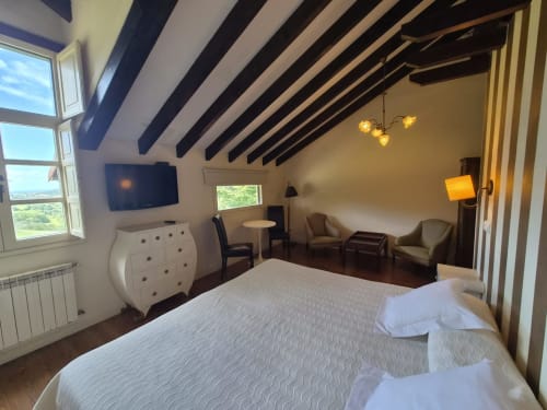 Luxury double room with sea views at Posada Torre del Milano, Comillas. Modern beamed ceiling, bed, seating area, and windows