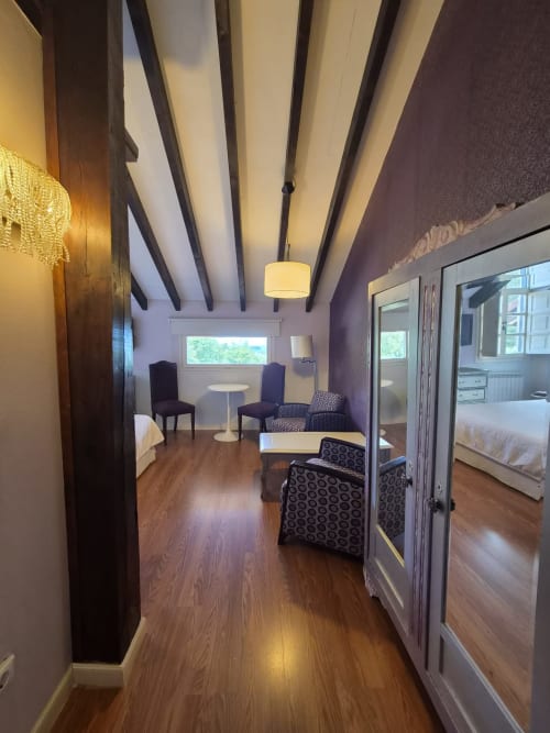 Modern double room with sea views at Posada Torre del Milano in Comillas, featuring wooden beams, purple accents, and