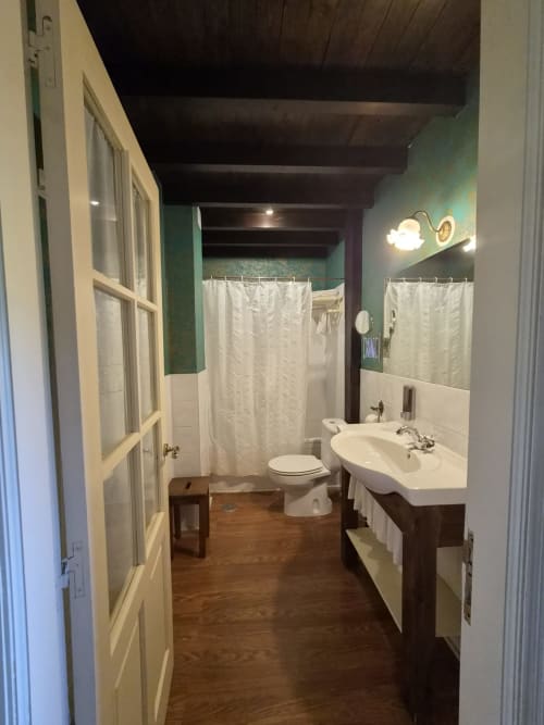 Bathroom at Posada Torre del Milano in Comillas with sink, toilet, shower, and wooden flooring