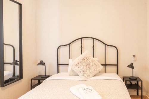 Charme da Graça hotel room in Costa de Caparica with metal frame bed, cream bedding, and black bedside lamps