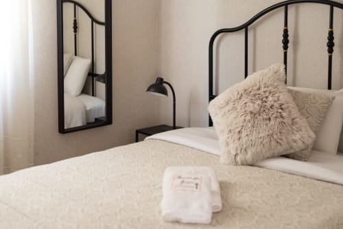Modern bedroom at Charme da Graça hotel in Lisboa with black metal bed frame, fluffy pillow, and mirror