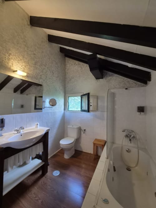 Spacious bathroom at Posada Torre del Milano with sink, toilet, bathtub, and exposed wooden beams