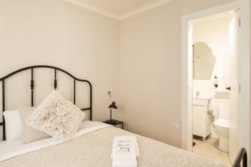 Charme da Graça hotel room in Costa de Caparica with bed, black headboard, and ensuite bathroom