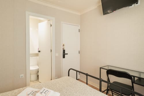 Charme da Graça hotel room in Costa de Caparica with bed, TV, desk, and ensuite bathroom