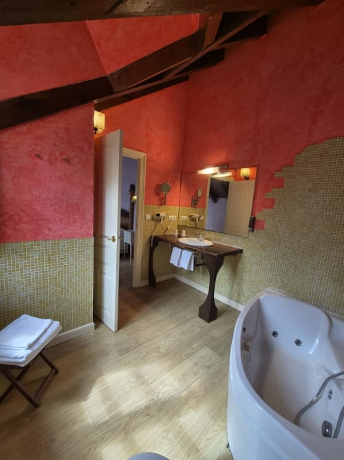 Spacious bathroom with red walls, green tile, soaking tub, and pedestal sink at Posada Torre del Milano in Comillas