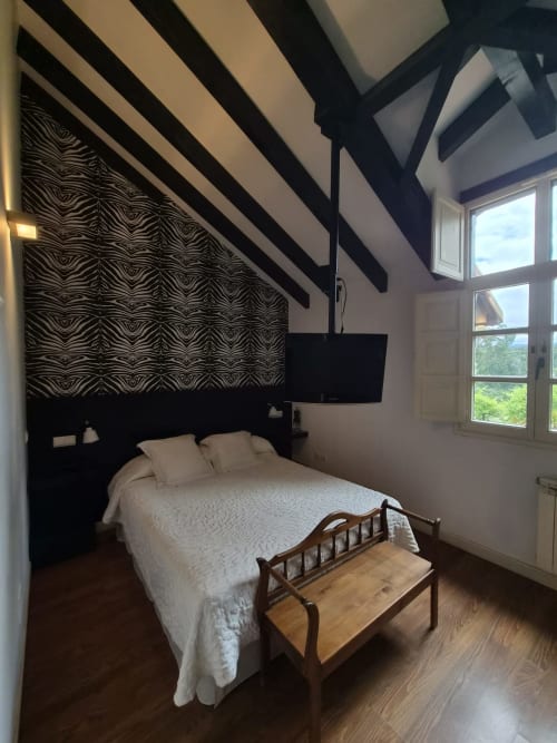 Modern bedroom at Posada Torre del Milano in Comillas with zebra-striped headboard, white bedding, wooden bench, and mountain