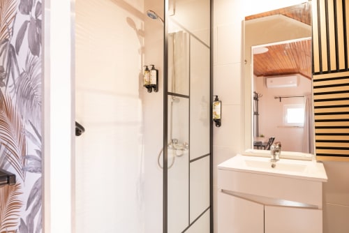 Modern bathroom at Charme da Graça hotel in Costa de Caparica with shower, sink, and wooden accents