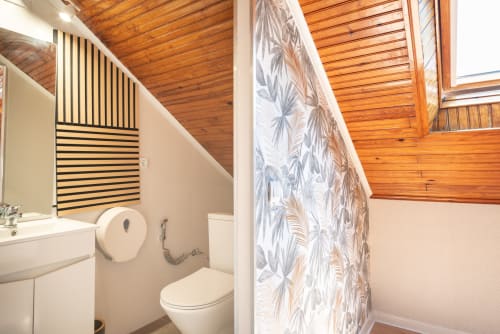 Modern bathroom at Charme da Graça hotel in Costa de Caparica, Lisbon with wooden ceiling and botanical shower curtain