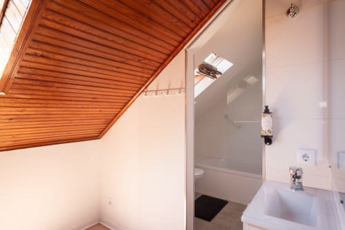 Modern bathroom with wooden ceiling at Charme da Graça hotel in Costa de Caparica, Lisbon, featuring sink and shower
