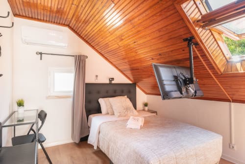 Cozy attic bedroom at Charme da Graça, Lisboa with wooden ceiling, TV, desk, and modern amenities
