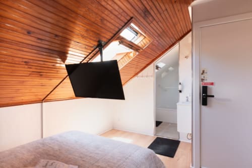 Charme da Graça hotel room in Costa de Caparica with wooden ceiling, bed, skylight, and modern amenities including