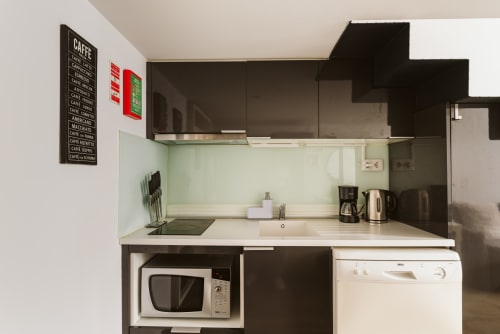 Modern kitchenette at Charme da Graça hotel in Belém, Lisboa, with dark cabinetry, coffee menu sign, microwave, and