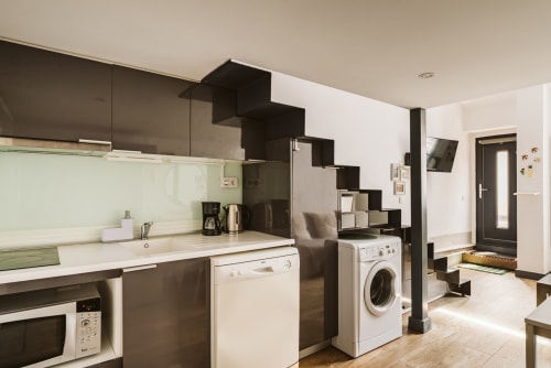Modern open-plan kitchen and laundry area at Charme da Graça apartment in Belém, Lisboa with black cabinetry and white