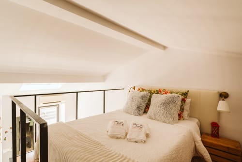 Charme da Graça bedroom in Belém, Lisboa with queen bed, fluffy pillows, wooden nightstand, and modern sloped ceiling