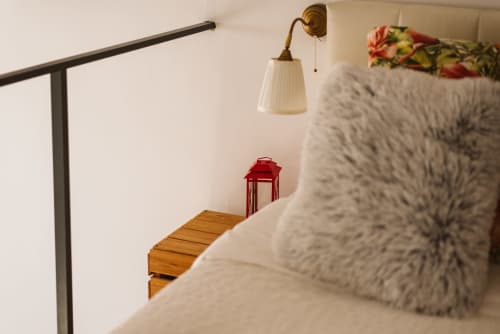 Cozy bedroom at Charme da Graça hotel in Lisbon with plush pillows, brass wall lamp, and wooden bench