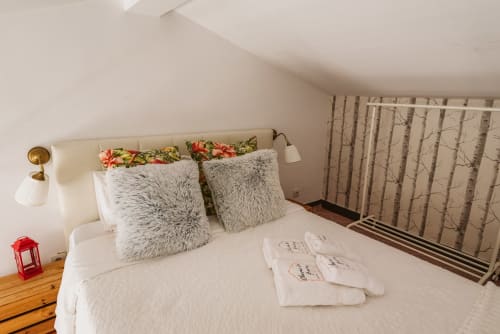Cozy bedroom at Charme da Graça hotel in Lisbon with white bedding, fluffy pillows, floral accents, and birch curtains