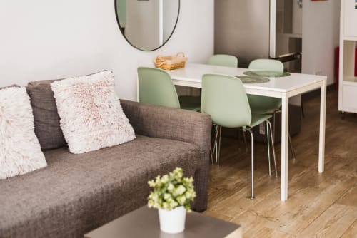 Modern apartment living area at Charme da Graça, Belém Lisboa, with gray sofa, green chairs, white table, and wooden
