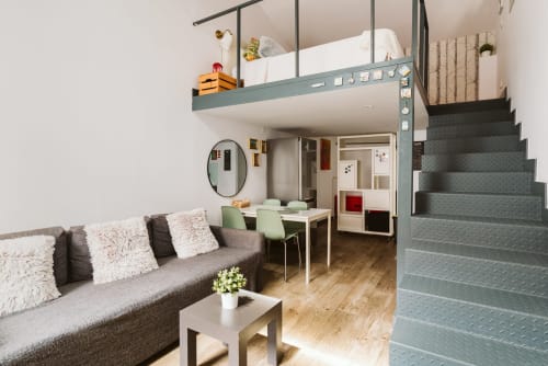 Modern loft apartment at Charme da Graça in Lisbon with mezzanine bedroom, gray sofa, dining area, and metal staircase