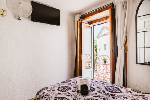 Charme da Graça hotel room in Lisboa with double bed, balcony view, TV, and wooden door opening to terrace