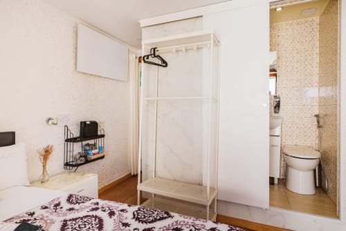 Private en-suite bathroom with shower in Charme da Graça hotel room, Lisboa. Beige tile walls, white fixtures, and wooden