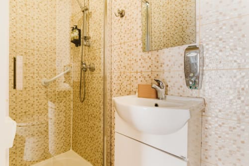 Modern bathroom with mosaic tile walls, walk-in shower, white sink, and soap dispenser at Charme da Graça hotel in Lisboa