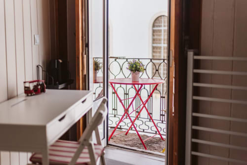 Modern balcony view at Charme da Graça hotel in Lisbon with red chair and potted flowers overlooking city
