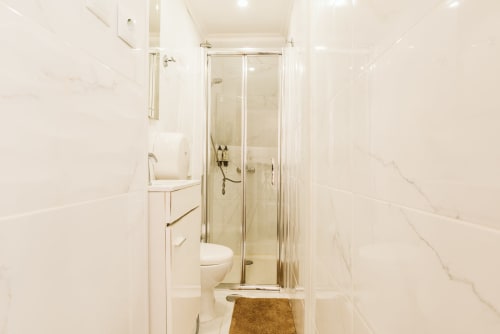 Modern ensuite bathroom at Charme da Graça hotel in Lisbon with walk-in shower, white marble tiles, and vanity.