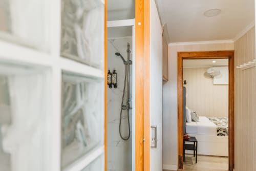 Charme da Graça hotel room in Lisbon with en-suite bathroom, marble shower, and view of bed through wooden doorframe