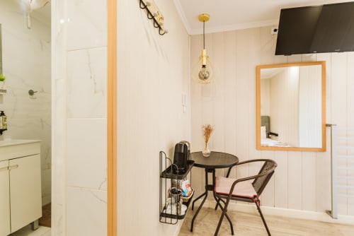 Modern hotel room at Charme da Graça, Lisboa, featuring ensuite bathroom, small dining area with table and chairs, mirror,