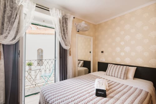 Charme da Graça hotel room in Lisbon with double bed, beige wallpaper, balcony doors, and city view